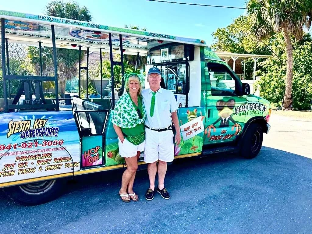 Happy couple riding a Frog Hop trolley on Siesta Key
